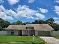 Charming single-story home featuring a well-manicured lawn and an attached two-car garage at 827 Creekside Ln, Palm Harbor, FL 34684