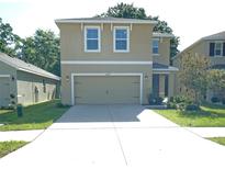 Two-story home with a beige exterior, two-car garage, and a spacious driveway at 10928 Carlton Fields Dr, Riverview, FL 33579