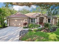 Charming single-story home featuring a well-manicured lawn, mature trees, and a welcoming two-car garage at 2222 Longmore Cir, Valrico, FL 33596