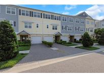 Townhomes with varied colors offer garages, tasteful landscaping and brick paver driveways under a blue sky at 4139 Rocky Shores Dr, Tampa, FL 33634