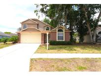 Charming two-story home features a brick facade and a two-car garage with lush front lawn at 4214 Longfellow Dr, Plant City, FL 33566