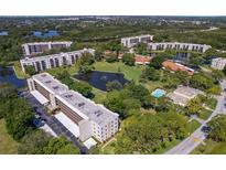 This aerial showcases a community with mature trees, serene ponds, and well-maintained buildings and pool at 5920 80Th N St # 103, St Petersburg, FL 33709