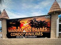 Entrance sign for Manhattan Palms Condominiums with palm tree imagery and decorative brick pillars at 7210 N Manhattan Ave # 1311, Tampa, FL 33614