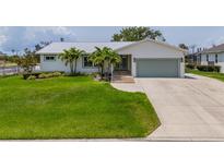 Charming single-story home featuring a lush green lawn, metal roof, and meticulously maintained landscaping with palm trees at 817 Eagle Ln, Apollo Beach, FL 33572