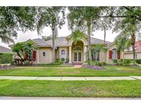 Charming home with lush landscaping, manicured lawn, and inviting double-door entryway framed by classic columns at 16322 Heathrow Dr, Tampa, FL 33647