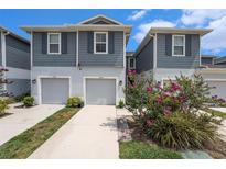 Charming two-story townhome showcasing a gray exterior, inviting garages, and vibrant flowering landscaping at 2140 Laceflower Dr, Brandon, FL 33510