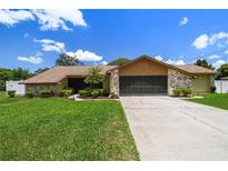 Charming one-story home features a two-car garage, stone accents, landscaped yard, and a well-manicured lawn at 2436 Covington Ave, Spring Hill, FL 34608