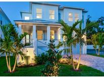 Charming two-story home with a well-manicured lawn, lush tropical landscaping, and inviting front porch at twilight at 509 Buckingham E Ave, Oldsmar, FL 34677