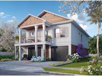Two story home with a two car garage, front porch, and beautiful landscaping on a sunny day at 600 Banana St, Tarpon Springs, FL 34689