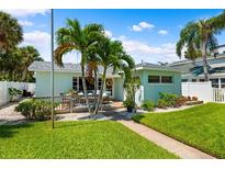 Charming home featuring a lovely deck with outdoor seating, lush lawn, and tropical landscaping at 106 13Th Ave, St Pete Beach, FL 33706