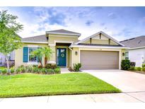 Inviting single-story home featuring a well-manicured lawn, blue door, and a two-car garage at 33518 Castaway Loop, Wesley Chapel, FL 33543