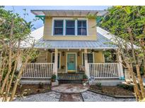 Charming two-story home with a cozy front porch, a metal roof, and a blue front door at 1038 Crescent Lake N Dr, St Petersburg, FL 33701