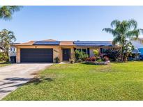 Charming single-story home featuring a well-manicured lawn, solar panels, and a two-car garage at 2401 66Th S Ave, St Petersburg, FL 33712