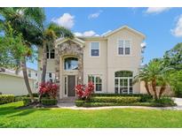 Stunning two-story home with stone accents, lush landscaping, and mature palm trees at 4206 W Sevilla St, Tampa, FL 33629