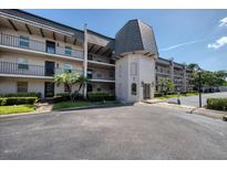 Condo building featuring neutral stucco, black iron railings, and mature landscaping creating a welcoming curb appeal at 712 Cordova Greens # 712, Largo, FL 33777