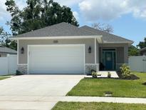 Charming single-story home featuring an attached two-car garage, a teal front door, and well-maintained landscaping at 7635 N 55Th N St, Pinellas Park, FL 33781