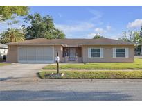 Charming single-story home featuring a well-manicured lawn, shutters, and an attached garage at 12817 Lake Tree Ln, Hudson, FL 34669