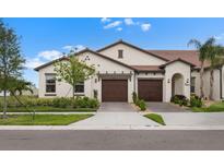 Inviting home featuring a clay tile roof, two-car garage, and well-maintained landscaping at 17222 Holly Well Ave, Wimauma, FL 33598
