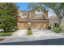 Inviting tan two-story home featuring a two-car garage and well-maintained landscaping at 18939 Duquesne Dr, Tampa, FL 33647