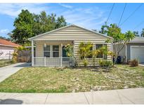 Charming single-story home with light beige siding, a well-manicured lawn, and a cute white picket fence at 2604 E Chelsea St, Tampa, FL 33610