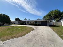 Charming single-story home with a well-manicured front lawn and a long driveway leading to an attached garage at 378 79Th Ne Ave, St Petersburg, FL 33702
