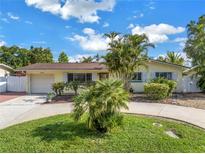Charming single-story home with a circular driveway, lush landscaping, and attached one car garage at 3843 Neptune Se Dr, St Petersburg, FL 33705