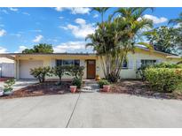 Charming single-story home showcasing a manicured lawn, mature trees, and a welcoming entryway at 3843 Neptune Se Dr, St Petersburg, FL 33705