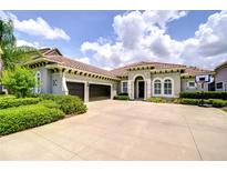 Stunning single-story home boasting a three-car garage and tile roof, set against a blue sky at 5728 Watercolor Dr, Lithia, FL 33547