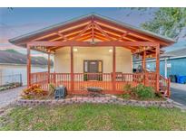 Inviting front porch with craftsman style wood beams and trim, and decorative landscaping at 7010 N Hubert Ave, Tampa, FL 33614
