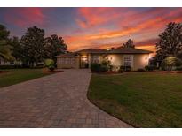 Beautiful single-story home with brick-paved driveway and manicured landscaping under a vibrant sunset sky at 8308 Mobile Cir, Weeki Wachee, FL 34613