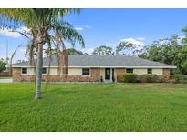 Charming single-story home featuring a lush green lawn and a stone and siding exterior at 903 Tomahawk Trl, Brandon, FL 33511