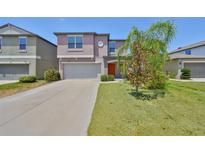 Charming two-story home with a well-manicured lawn, a two-car garage, and an orange front door at 10210 White Linen Ave, Riverview, FL 33578