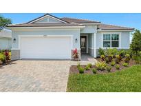 Charming single-story home featuring a paver driveway, well-manicured lawn, and a two-car garage at 11737 Myakka Blue Dr, Venice, FL 34293