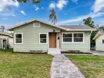 Charming single-story home features a stone walkway, light green siding, and a well-maintained front yard at 1267 Woodlawn Ter, Clearwater, FL 33755
