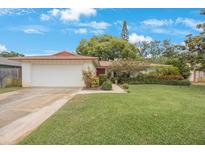 Charming single-story home featuring a well-manicured lawn, two-car garage and vibrant landscaping at 13563 Cordova Dr, Largo, FL 33774