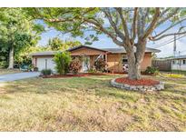 Charming single-story home featuring a well-manicured lawn, mature tree, and attached two-car garage at 14000 104Th Ave, Largo, FL 33774