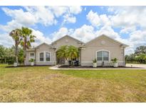 Charming home featuring lush landscaping, a well-maintained lawn, and mature palm trees at 2214 132Nd E Pl, Parrish, FL 34219