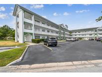 Well-maintained exterior with white facade, green trim, balconies, and ample parking space under a partly cloudy sky at 2469 Franciscan Dr # 59, Clearwater, FL 33763