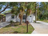 Charming white brick home featuring a manicured lawn and tropical landscaping at 5013 W Mccoy St, Tampa, FL 33616