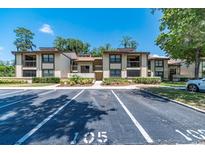 A condominium with two stories, a parking lot, sidewalks and green space at 105 Woodlake Wynde, Oldsmar, FL 34677