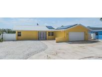 Charming yellow home featuring a metal roof, solar panels, white rock landscaping, and a paved driveway at 1421 Sea Gull S Dr, St Petersburg, FL 33707