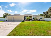 Traditional home with a three-car garage, large lawn, mature landscaping, and neutral color scheme at 1521 Avondale Ridge Dr, Plant City, FL 33567