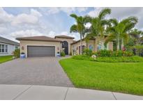 Charming home with a manicured lawn, colorful flowerbeds, paver driveway, and a two car garage at 15303 Valencia Del Sol St, Wimauma, FL 33598