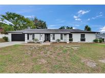 Charming single-story home with a black garage, black framed front door, black shutters, and a well-maintained lawn at 2219 Summit View Dr, Valrico, FL 33596
