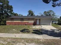 A single story home with boarded up windows and a red brick foundation with tan siding at 3308 E Frierson Ave, Tampa, FL 33610