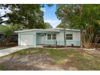 Charming single-story home featuring a light blue and white exterior, complemented by a well-maintained front yard and mature trees at 341 Wertz Dr, Largo, FL 33771