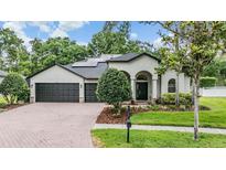 Charming single-story home features a brick driveway, a manicured lawn, and a three-car garage at 5109 Hartwell Loop, Land O Lakes, FL 34638