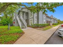 Beautiful condo building with light gray siding, white stairwell, and landscaped grounds at 6001 Laketree Ln # B, Temple Terrace, FL 33617