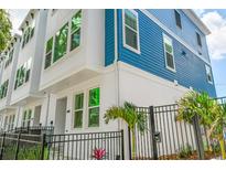 Charming townhome showcasing its modern design, blue accents, and fenced front yard at 6605 N Nebraska Ave # 25, Tampa, FL 33604