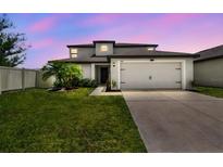 Charming two-story home showcasing a well-manicured lawn, two-car garage, and neutral color scheme at 1009 Wynnmere Walk Ave, Ruskin, FL 33570